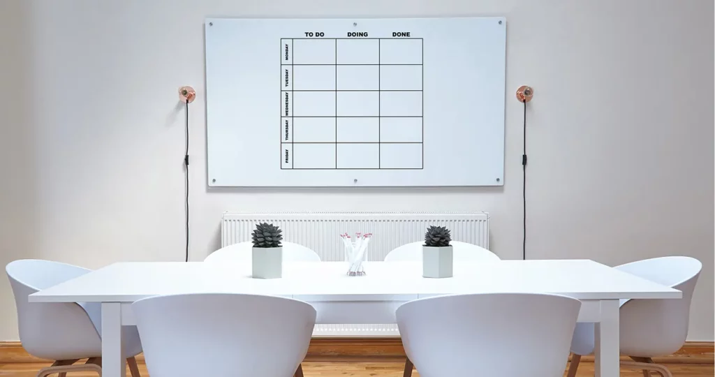 Tafel met stoelen en aan de muur een rooster/agenda